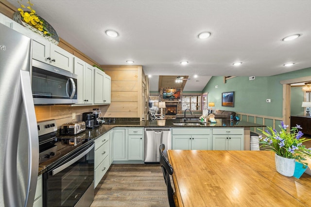 kitchen with white cabinetry, sink, stainless steel appliances, dark hardwood / wood-style flooring, and kitchen peninsula