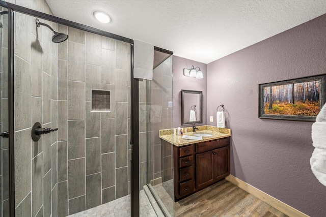 bathroom featuring wood-type flooring, vanity, a textured ceiling, and a shower with shower door