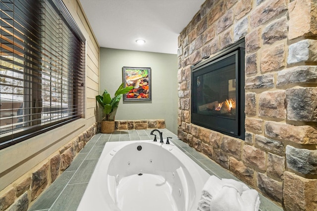 bathroom featuring a stone fireplace, a textured ceiling, and tiled bath