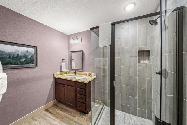 bathroom with walk in shower, vanity, a textured ceiling, and hardwood / wood-style flooring