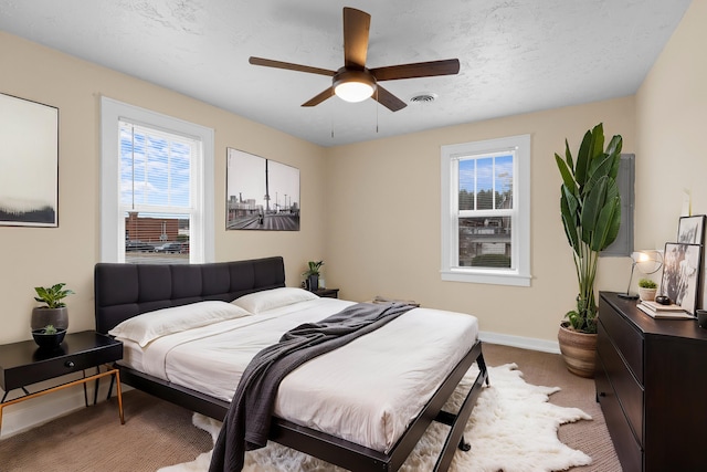 bedroom featuring carpet, visible vents, baseboards, ceiling fan, and a textured ceiling