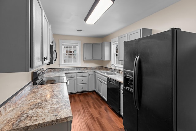 kitchen with visible vents, dark wood finished floors, gray cabinets, black appliances, and a sink