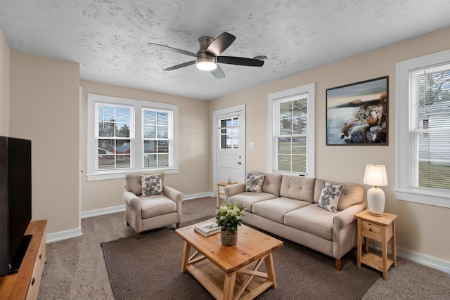 living room with carpet flooring, a ceiling fan, baseboards, and a textured ceiling