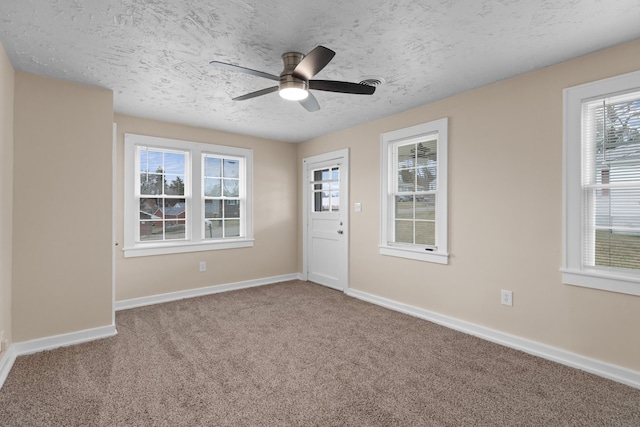 carpeted empty room with ceiling fan, a textured ceiling, and baseboards