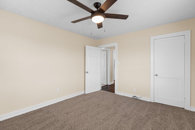 unfurnished bedroom featuring dark colored carpet, baseboards, and a ceiling fan