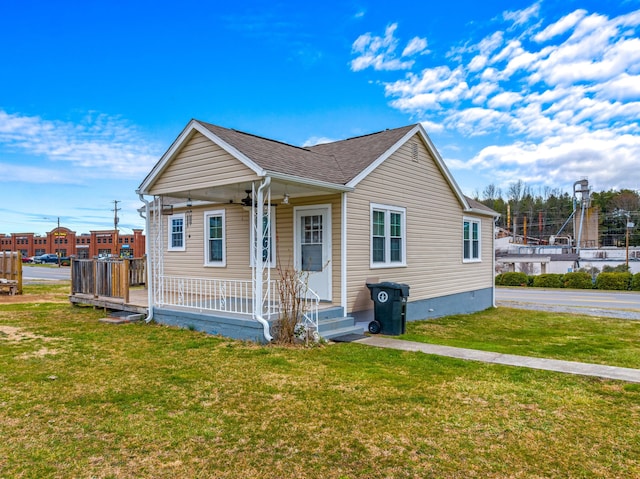 bungalow with a front yard, covered porch, and roof with shingles