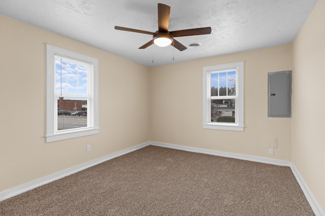 spare room with visible vents, baseboards, carpet floors, electric panel, and a textured ceiling