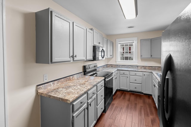 kitchen featuring black appliances, dark wood-style floors, visible vents, and gray cabinetry