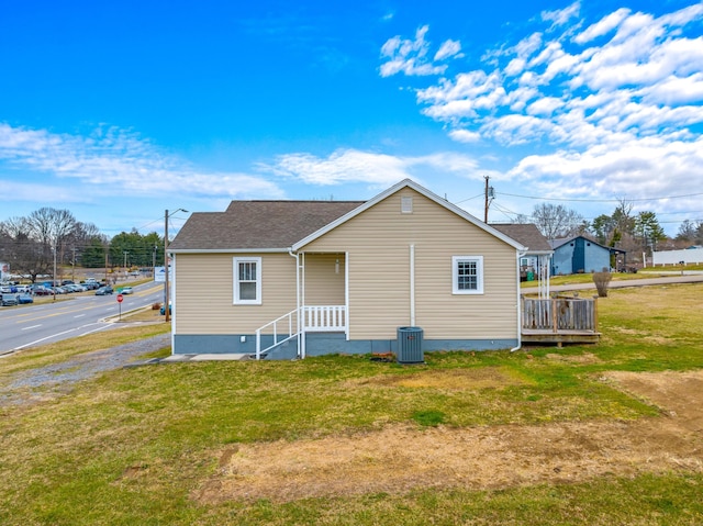 back of house with a yard, central AC unit, and a shingled roof