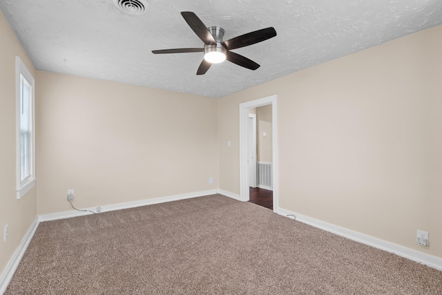 unfurnished room with visible vents, baseboards, a textured ceiling, and dark carpet