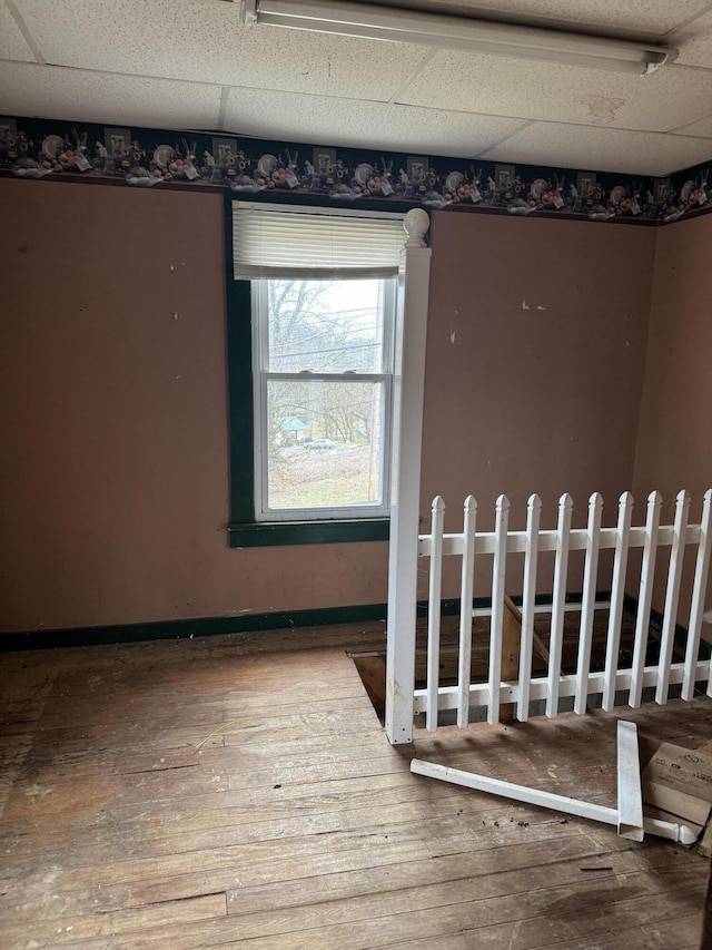 empty room with hardwood / wood-style flooring and a drop ceiling