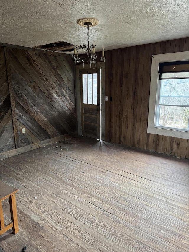 interior space with wood-type flooring, wood walls, and an inviting chandelier