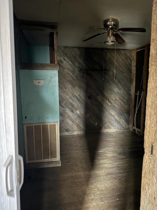 spare room with dark wood-type flooring, ceiling fan, and wood walls