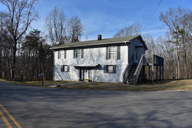 view of front of property featuring a deck, a chimney, and stairway