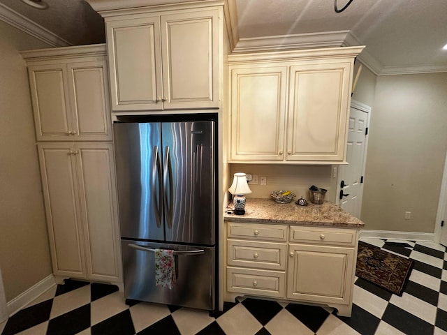 kitchen with baseboards, freestanding refrigerator, light floors, and cream cabinetry