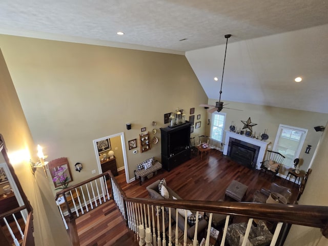 living area with ceiling fan, a fireplace, high vaulted ceiling, baseboards, and wood finished floors