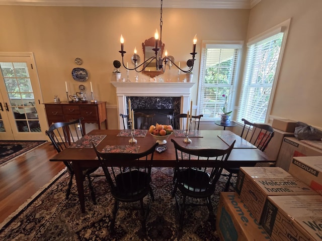 dining area featuring crown molding, a fireplace, wood finished floors, and a notable chandelier