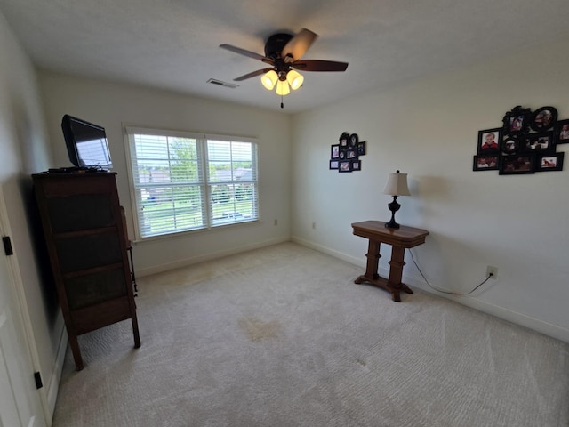 interior space featuring baseboards, ceiling fan, light carpet, and visible vents