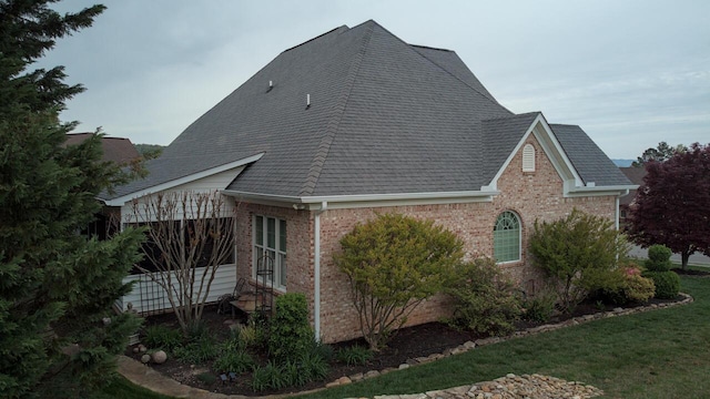 view of property exterior with roof with shingles, a garage, and brick siding