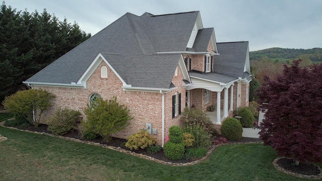 view of property exterior with a lawn, roof with shingles, and brick siding