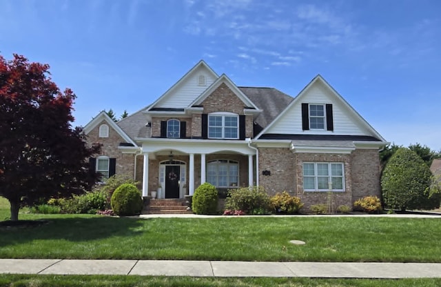 craftsman-style house with a porch, brick siding, and a front yard