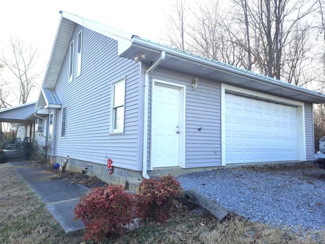 view of side of home featuring a garage and gravel driveway