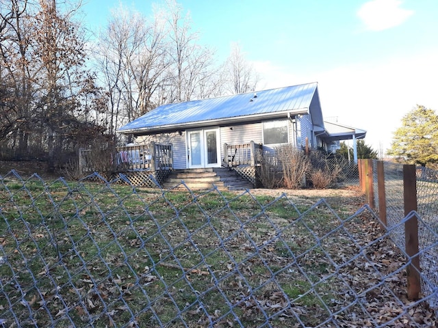 back of house with fence, metal roof, and a wooden deck