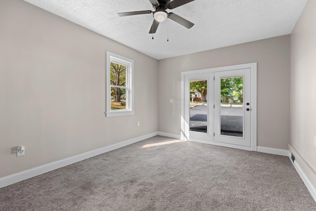 unfurnished room featuring ceiling fan, plenty of natural light, carpet, and a textured ceiling