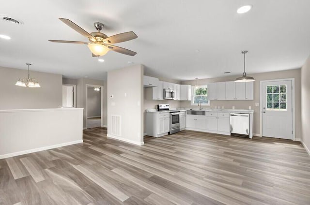 kitchen featuring pendant lighting, ceiling fan with notable chandelier, light wood-type flooring, white cabinetry, and stainless steel appliances