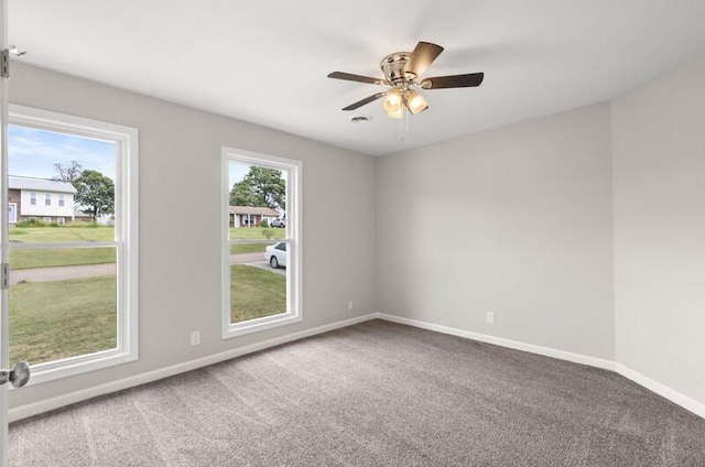 empty room with carpet flooring, a wealth of natural light, and ceiling fan