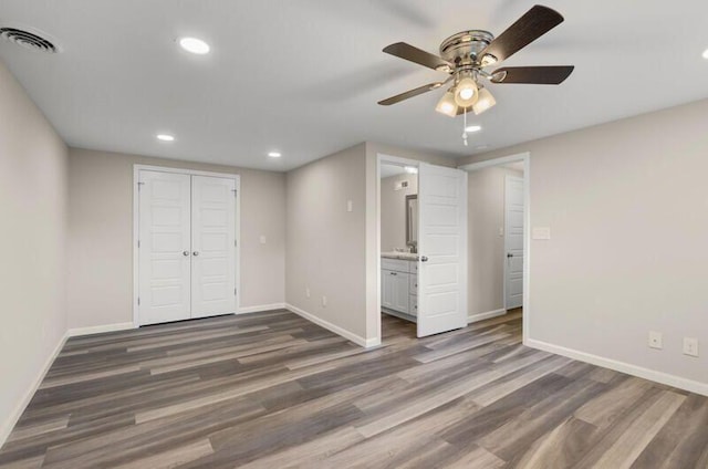 unfurnished bedroom featuring ceiling fan, dark hardwood / wood-style floors, ensuite bath, and a closet