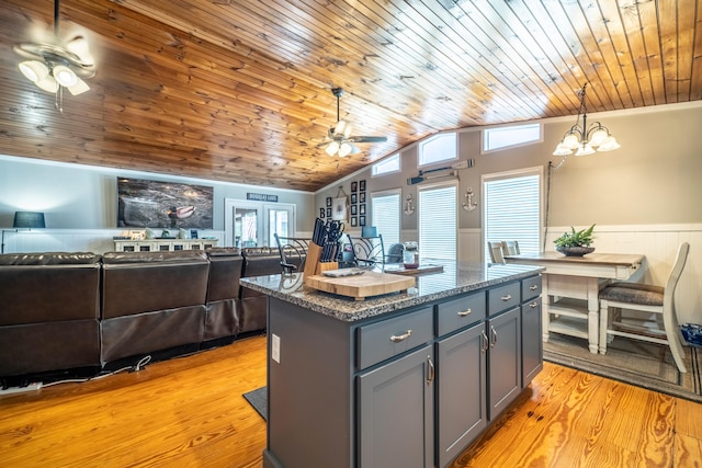 kitchen with light wood-type flooring, wood ceiling, vaulted ceiling, decorative light fixtures, and a center island