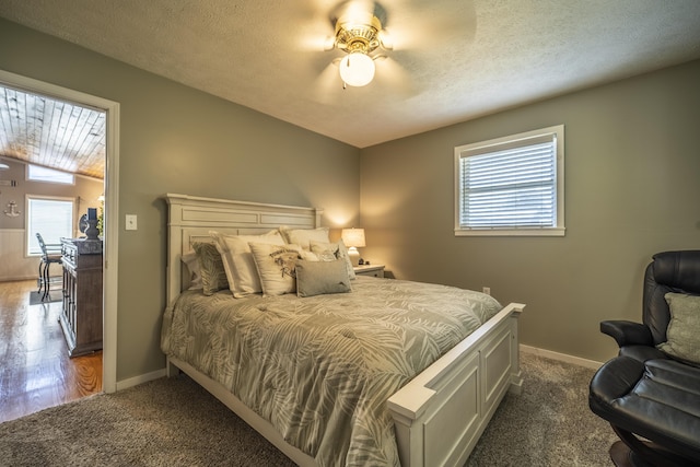 bedroom with dark colored carpet, ceiling fan, and a textured ceiling