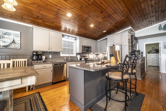 kitchen with a center island, stainless steel appliances, dark stone countertops, and wood ceiling