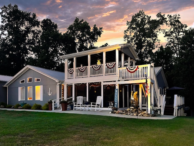 back house at dusk with a lawn, a patio area, and a wooden deck