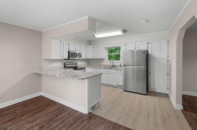 4061 Julian Ave, Morristown, TN 37814 - kitchen with appliances with stainless steel finishes, a sink, light wood-style floors, a peninsula, and ornamental molding