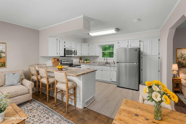 4061 Julian Ave, Morristown, TN 37814 - kitchen featuring appliances with stainless steel finishes, a sink, a peninsula, white cabinets, and crown molding