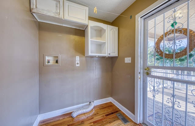 laundry area featuring visible vents, baseboards, hookup for a washing machine, wood finished floors, and cabinet space