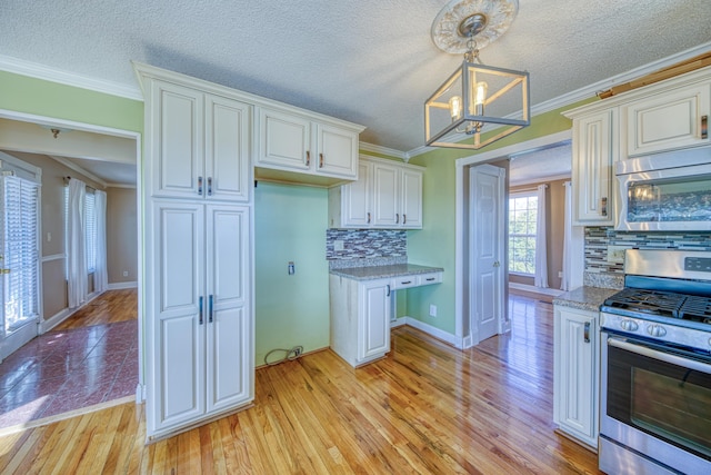 kitchen with light wood-style flooring, a notable chandelier, appliances with stainless steel finishes, and ornamental molding