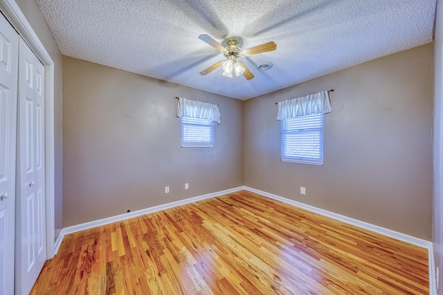 unfurnished bedroom featuring light wood finished floors, a textured ceiling, a closet, and baseboards