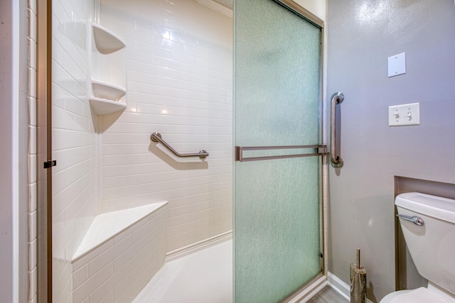 bathroom featuring toilet and a shower stall