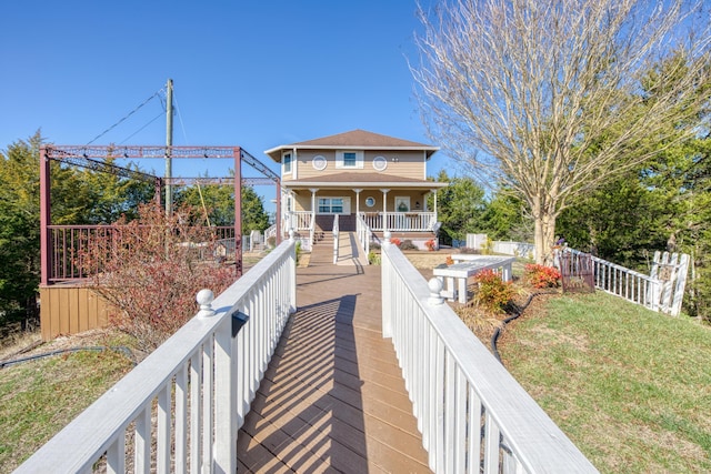 back of house featuring covered porch, a lawn, and fence