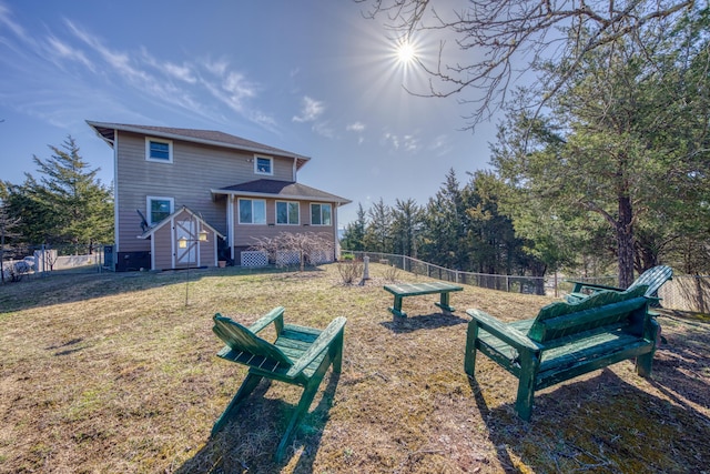 back of property with a lawn and fence