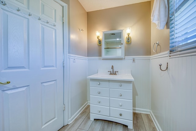 bathroom with vanity, wood finished floors, and wainscoting