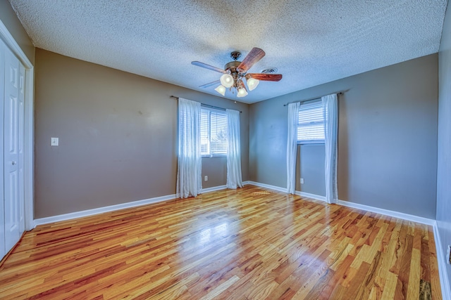 unfurnished bedroom with a textured ceiling, a ceiling fan, light wood-type flooring, and baseboards