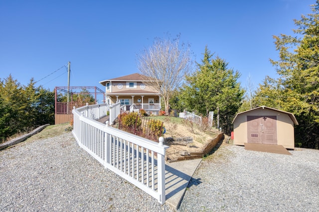 view of front facade with a storage shed, covered porch, an outdoor structure, and fence