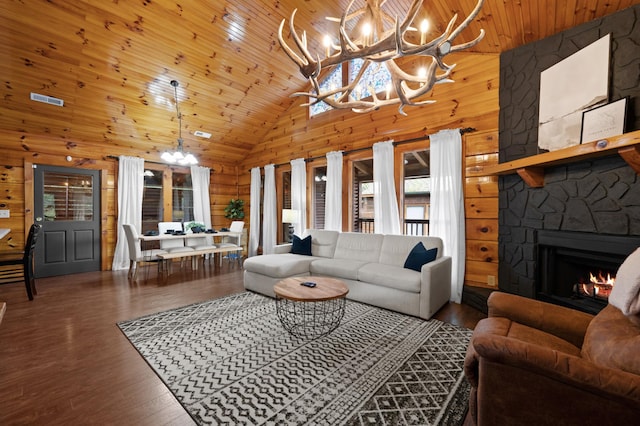 living room featuring a stone fireplace, wood walls, an inviting chandelier, wood-type flooring, and wooden ceiling