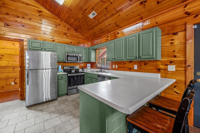 kitchen featuring sink, a kitchen bar, green cabinets, kitchen peninsula, and stainless steel appliances