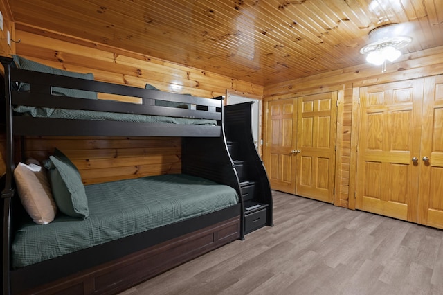 bedroom with wood ceiling, light wood-type flooring, and wood walls