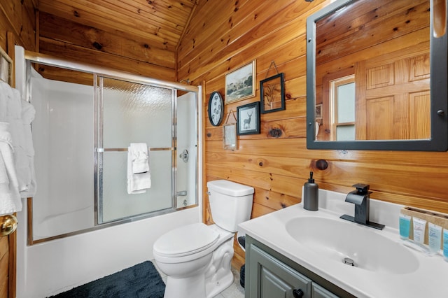 full bathroom with combined bath / shower with glass door, vanity, vaulted ceiling, toilet, and wood walls